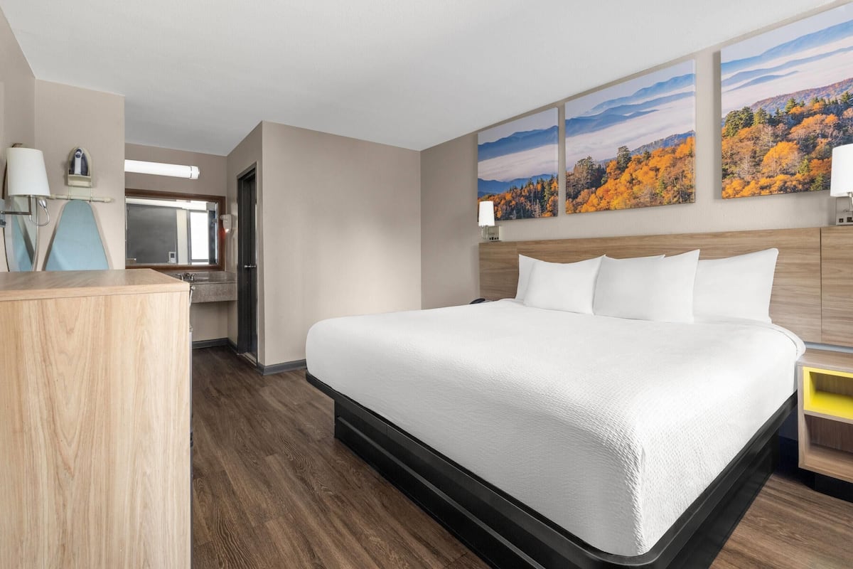 Habitación de hotel con una cama grande, suelo de madera, un escritorio y dos lámparas fijadas a la pared.