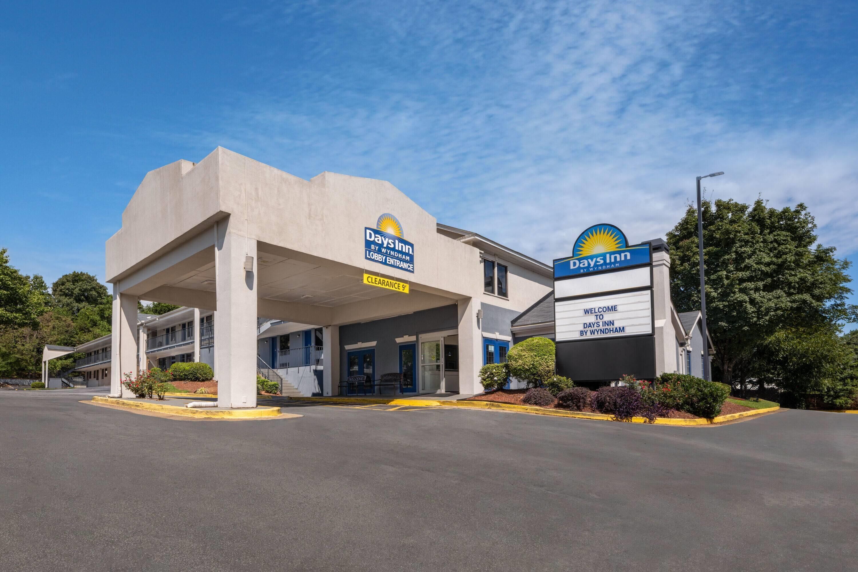 A Days Inn by Wyndham hotel with a clear entrance, a covered parking area, and a welcoming sign.
