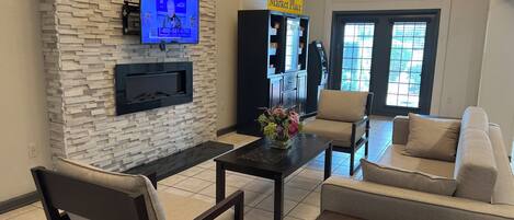 A living room with a stone wall, a flat-screen TV, a fireplace, a coffee table, and a sofa.