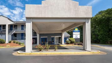 Un hotel Days Inn by Wyndham con entrada cubierta, estacionamiento y un edificio con puertas azules.