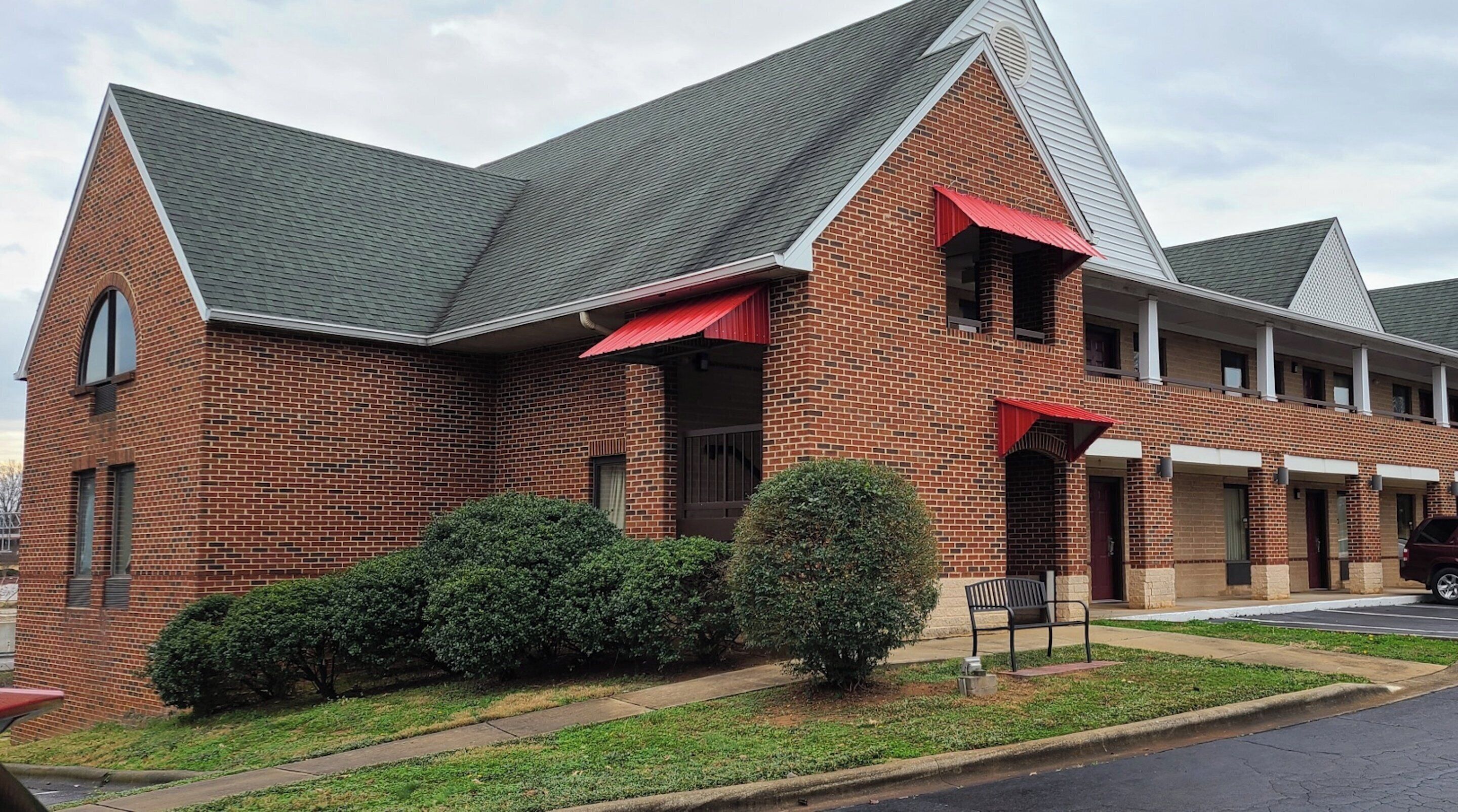 A brick building with a gabled roof and red awnings.