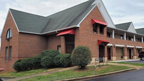 A brick building with a gabled roof and red awnings. - Red Roof Inn & Suites Cornelius – Lake Norman (Cornelius)