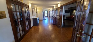 A hotel hallway with wooden floors, glass doors, and a reception desk. - Red Roof Inn & Suites Cornelius – Lake Norman (Cornelius)