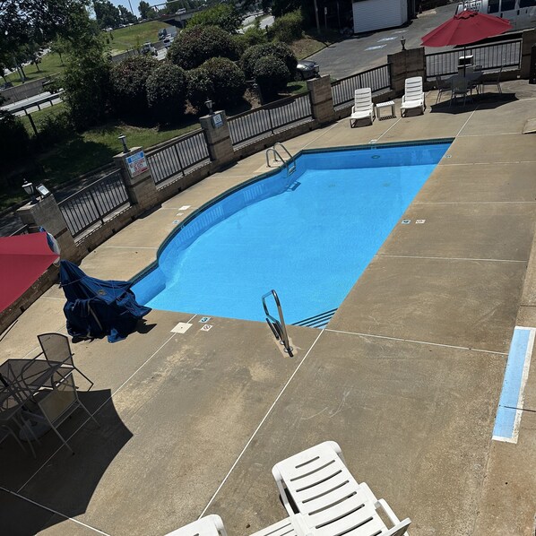 A swimming pool with lounge chairs and umbrellas, surrounded by a fence and greenery. - Red Roof Inn & Suites Cornelius – Lake Norman (Cornelius)