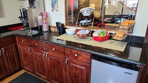 A kitchen with wooden cabinets, a dishwasher, and various kitchen items on the counter. - Red Roof Inn & Suites Cornelius – Lake Norman (Cornelius)