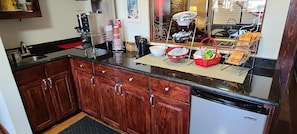 A kitchen with wooden cabinets, a dishwasher, and various kitchen items on the counter. - Red Roof Inn & Suites Cornelius – Lake Norman (Cornelius)