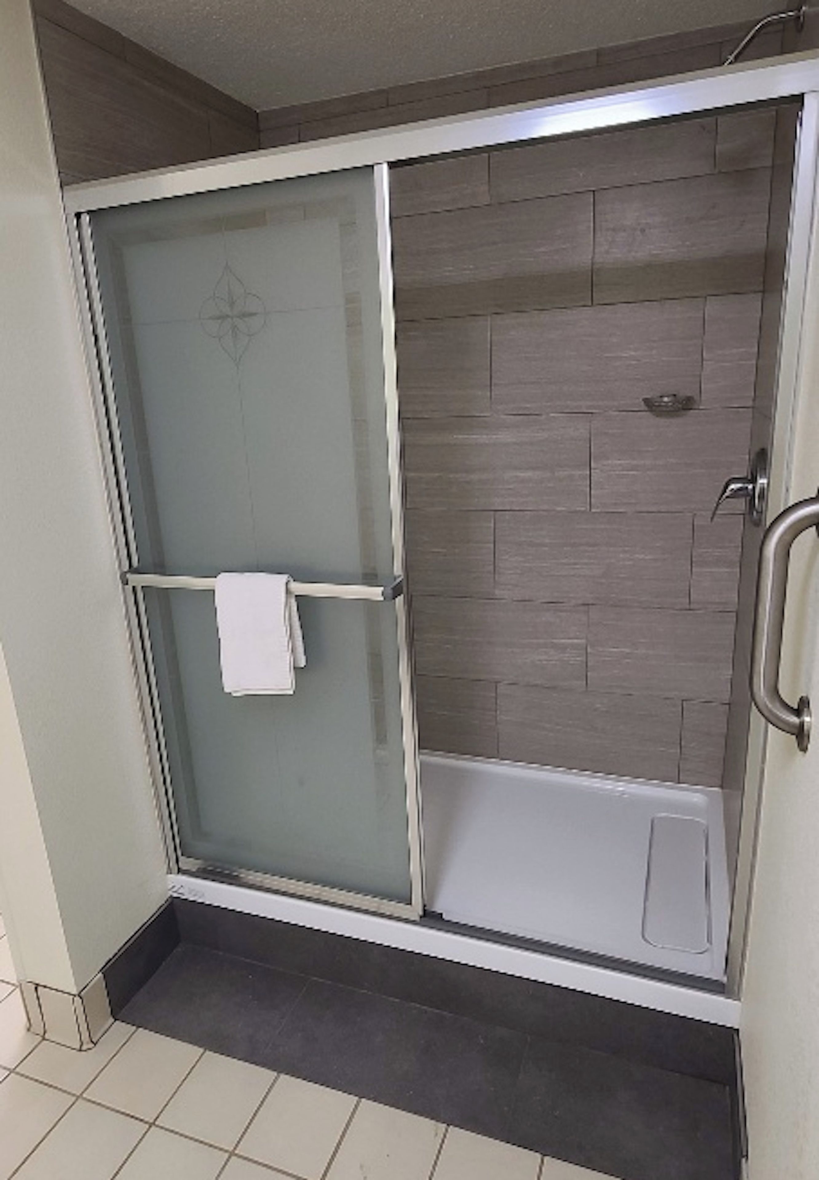 A glass-enclosed shower with a white towel hanging on the door handle.