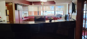 A reception desk with a computer, a cash register, and a window with a view of the outside. - Red Roof Inn & Suites Cornelius – Lake Norman (Cornelius)