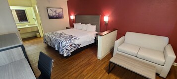 Habitación de hotel con una cama, una silla, una mesita de noche y una lámpara fijada a la pared.