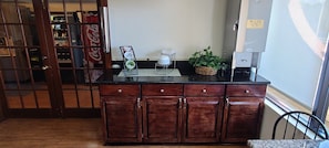 A kitchen with a wooden cabinet, a coffee machine, and a plant on the counter. - Red Roof Inn & Suites Cornelius – Lake Norman (Cornelius)