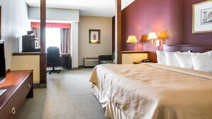Una habitación de hotel con cama, escritorio, silla y una mesa de trabajo con computadora.