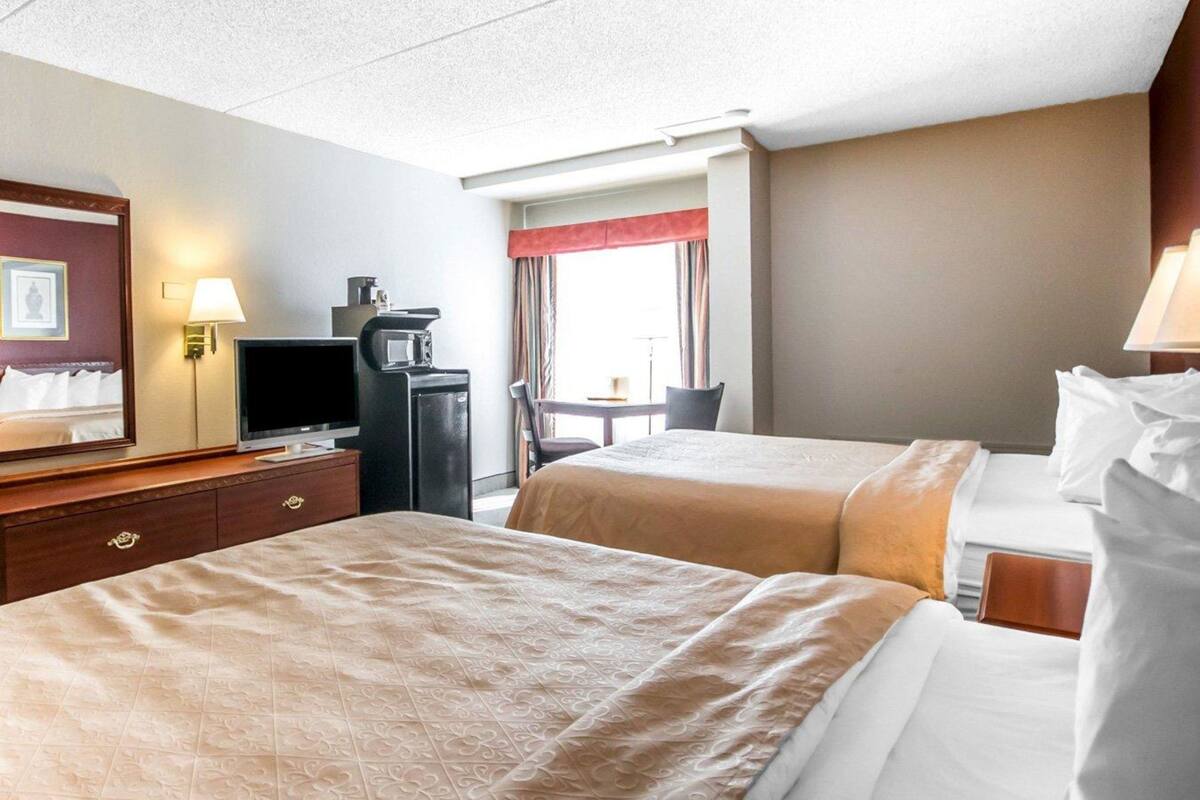 A hotel room with two beds, a desk with a computer, a TV, and a microwave.