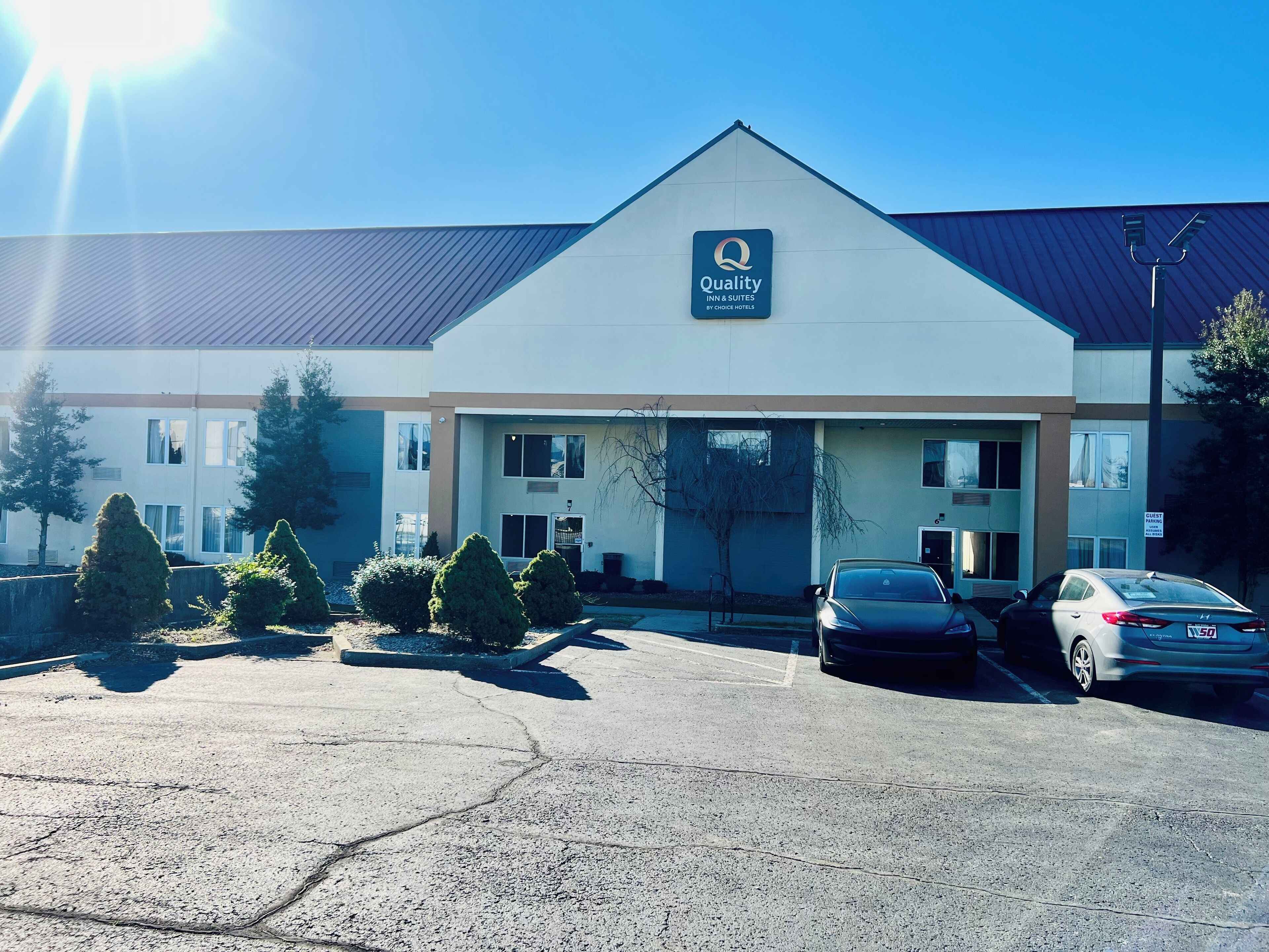 A Quality Inn & Suites by Choice Hotels building with a parking lot and two cars parked in front.