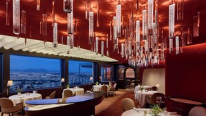 A modern restaurant with high ceilings, hanging crystal chandeliers, and a panoramic city view. - Rome Cavalieri, A Waldorf Astoria Hotel (Rome)