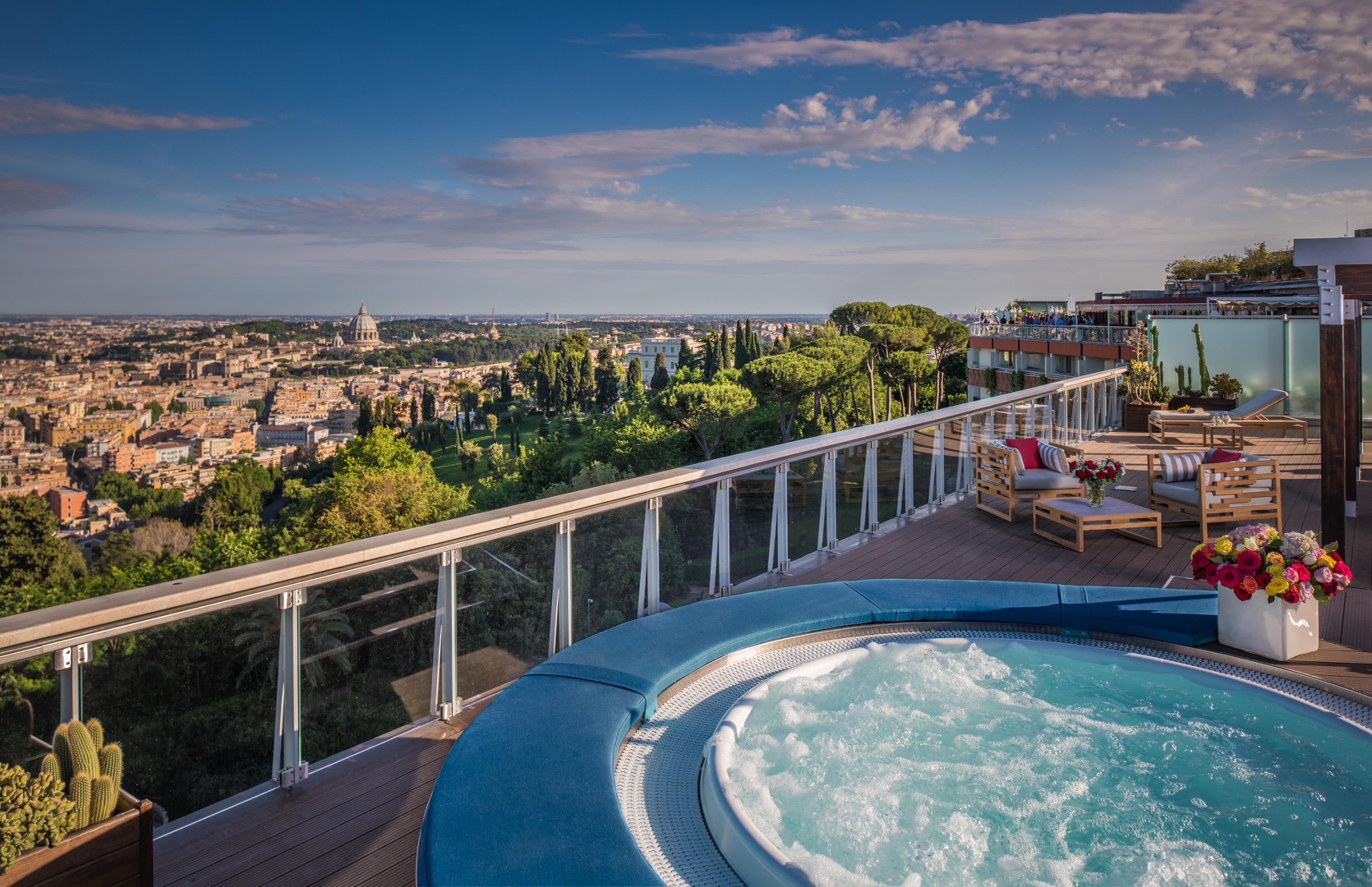 Una terrazza panoramica sul tetto con vasca idromassaggio, poltrone relax e vista sulla città.