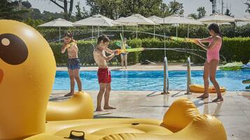 Zona de piscina con juguetes inflables y sombrillas.