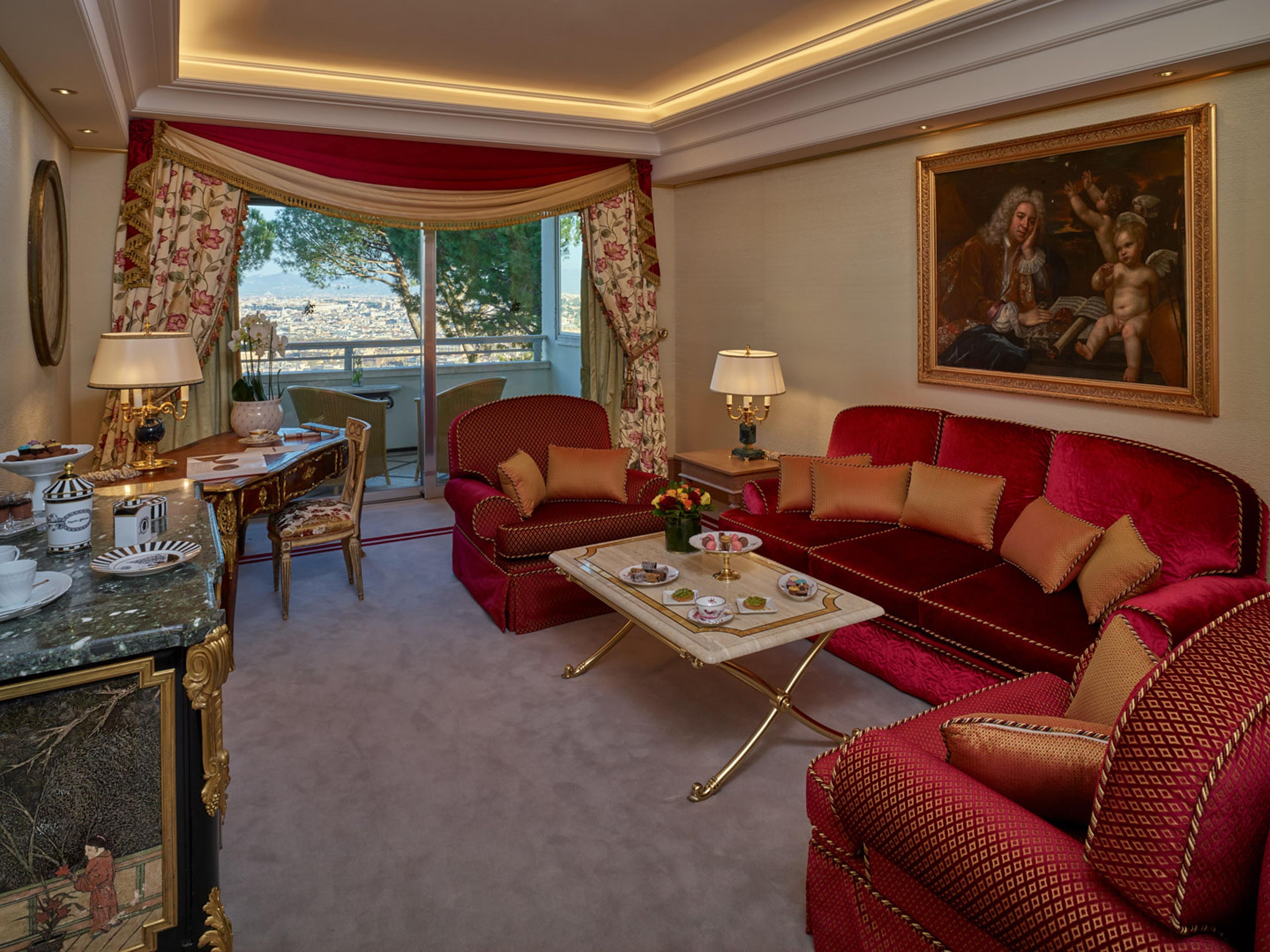 Een luxueuze woonkamer met een rode bank, een eethoek met een tafel en stoelen, en een groot schilderij aan de muur.