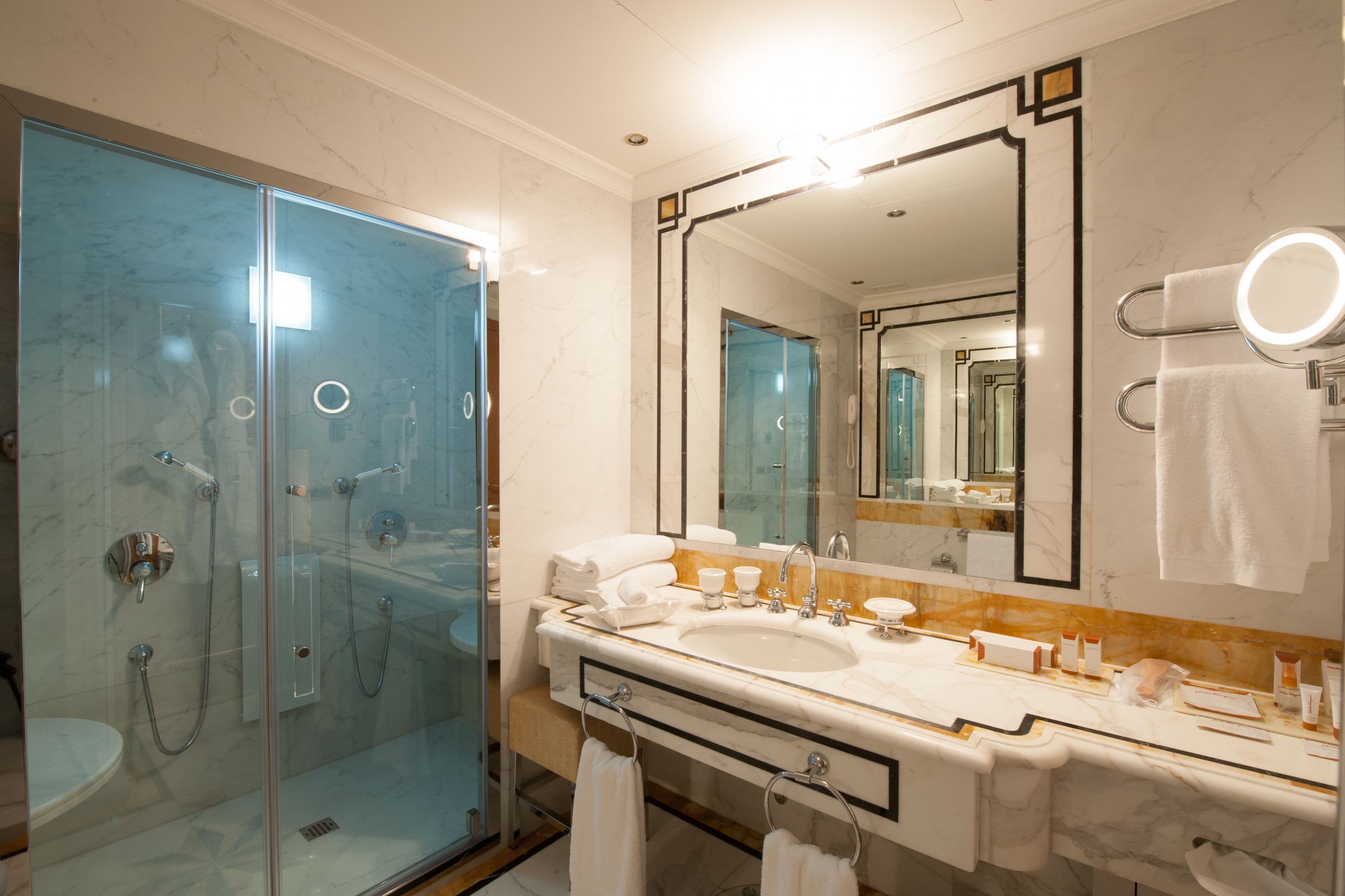 Un bagno moderno con doccia vetro, uno specchio grande e un lavabo con numerosi articoli da toilette.