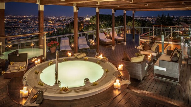 A rooftop terrace with a hot tub, lounge chairs, and candles. - Rome Cavalieri, A Waldorf Astoria Hotel (Rome)