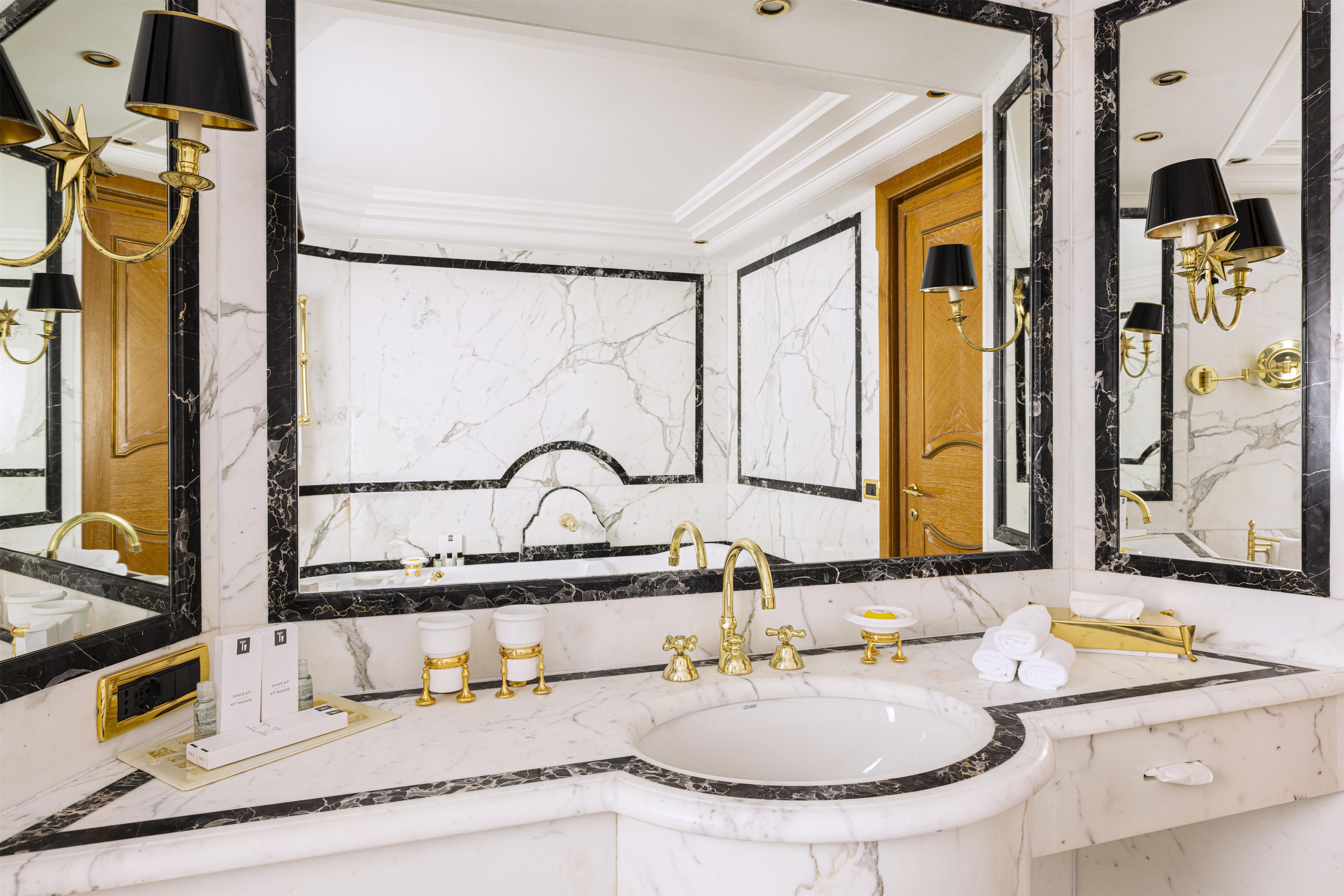 Un bagno lussuoso con un mobile vanità in marmo, accessori dorati e uno specchio grande.