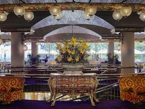 An ornate interior with a grand staircase, a large floral centerpiece, and classic furniture.