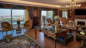 A luxurious living room with ornate furniture, a grand chandelier, and a large window offering a city view. - Rome Cavalieri, A Waldorf Astoria Hotel (Rome)