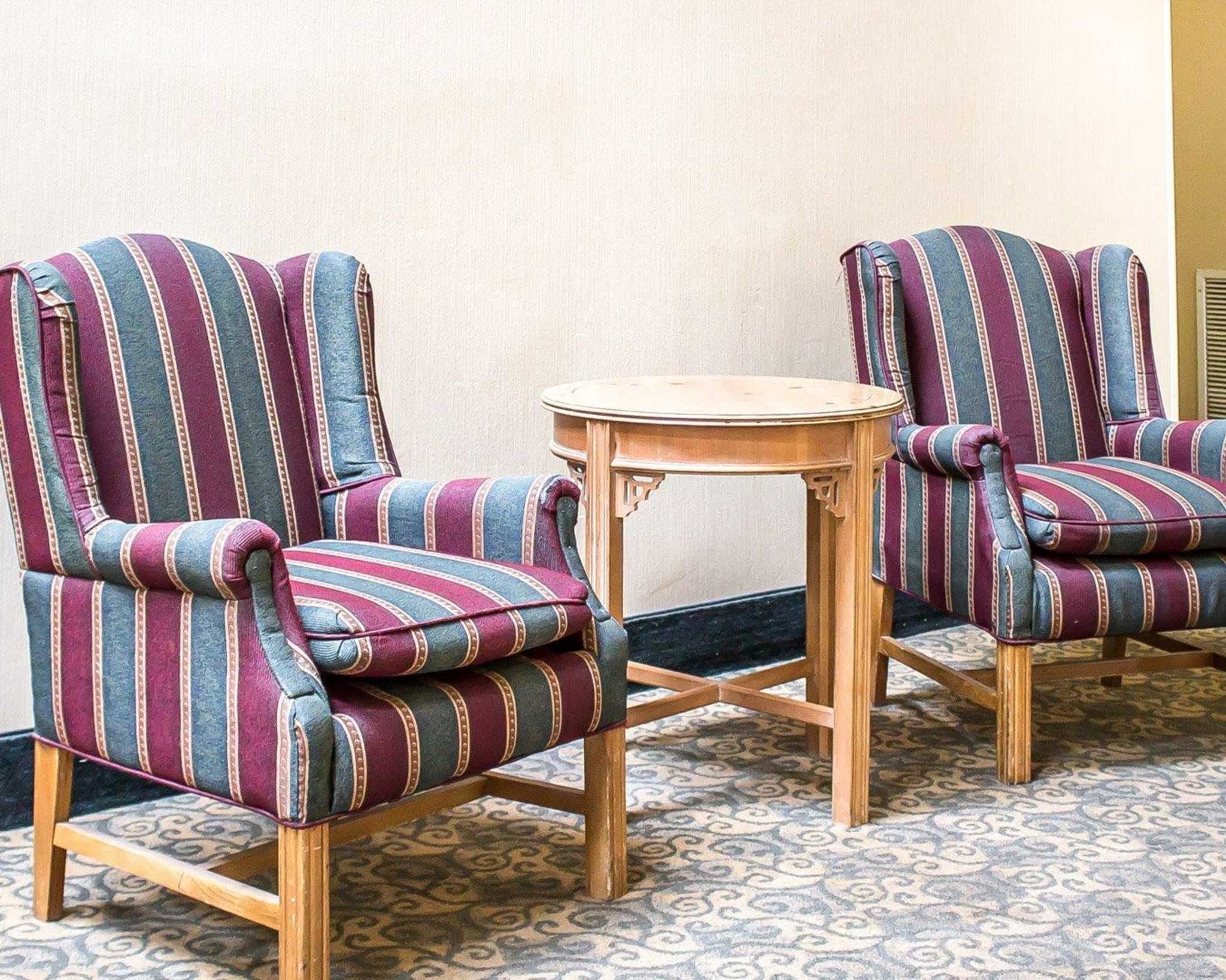 Deux fauteuils à rayures avec des pieds en bois, séparés par une petite table ronde.