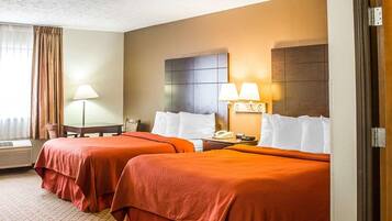 A hotel room with two beds, a desk, a lamp, and a phone on the nightstand.