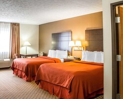 Habitación de hotel con dos camas, un escritorio, una lámpara y un teléfono en la mesita de noche.