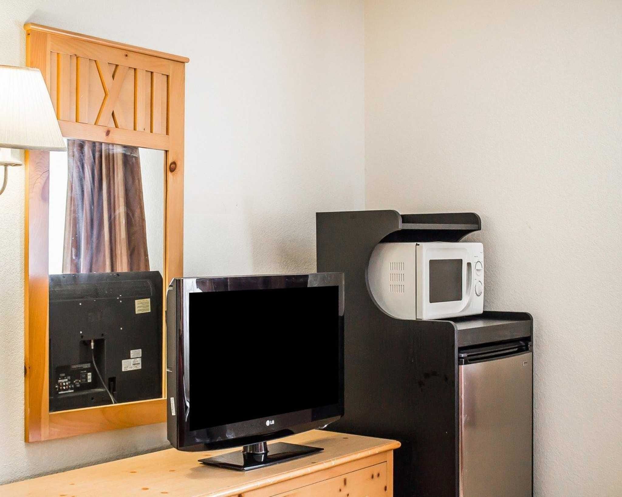 A room with a flat-screen TV, a microwave, and a refrigerator.
