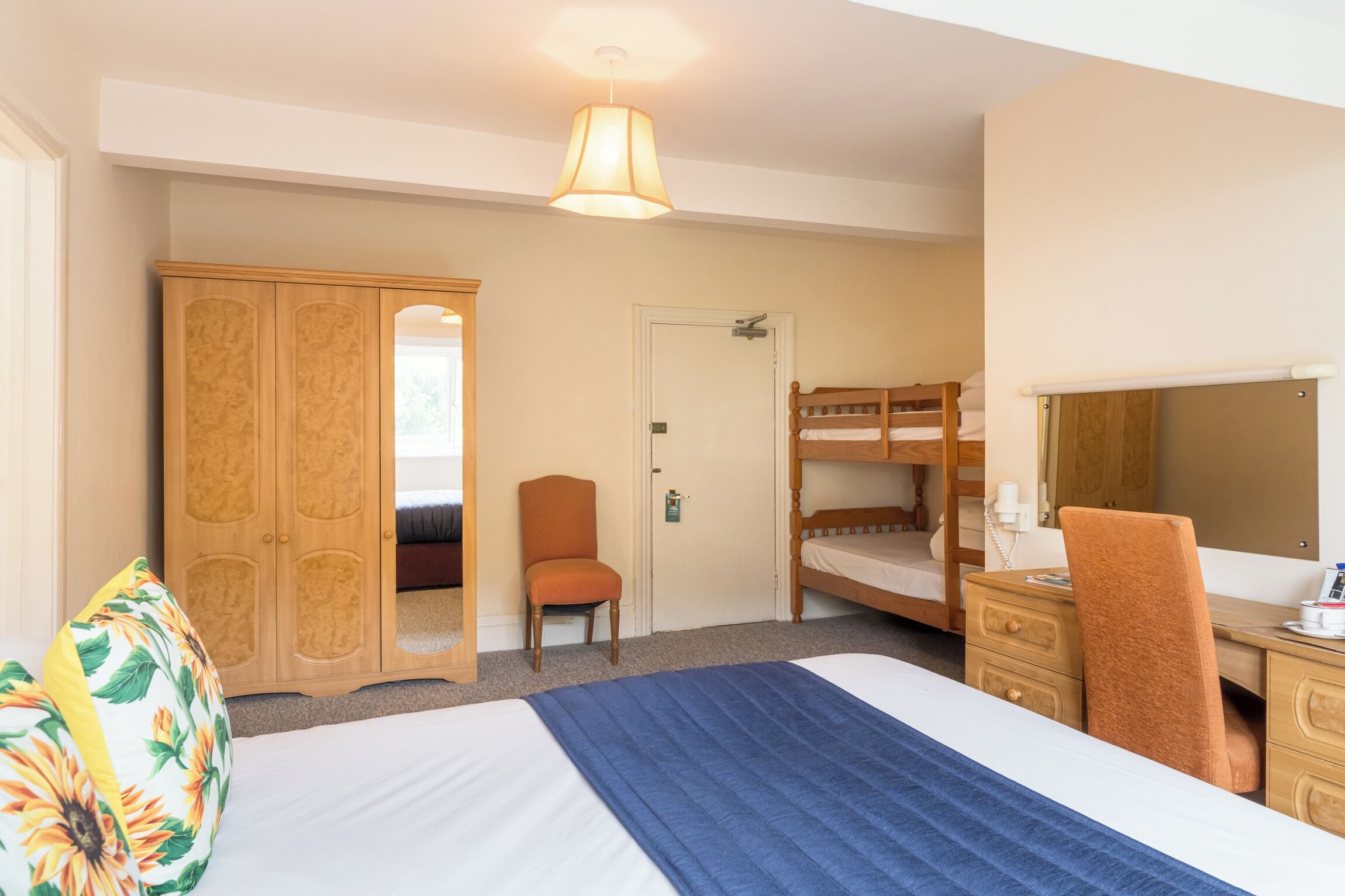A bedroom with a bed, a desk, a chair, a wardrobe, and a bunk bed.