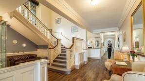 A grand staircase with a wooden handrail and white balusters, leading to a second floor. - Northfield Hotel (Minehead)
