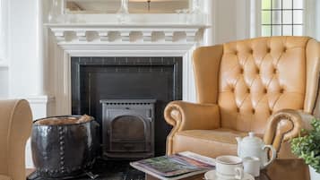 A room with a fireplace, a leather armchair, a table with a teapot, cups, and a magazine.