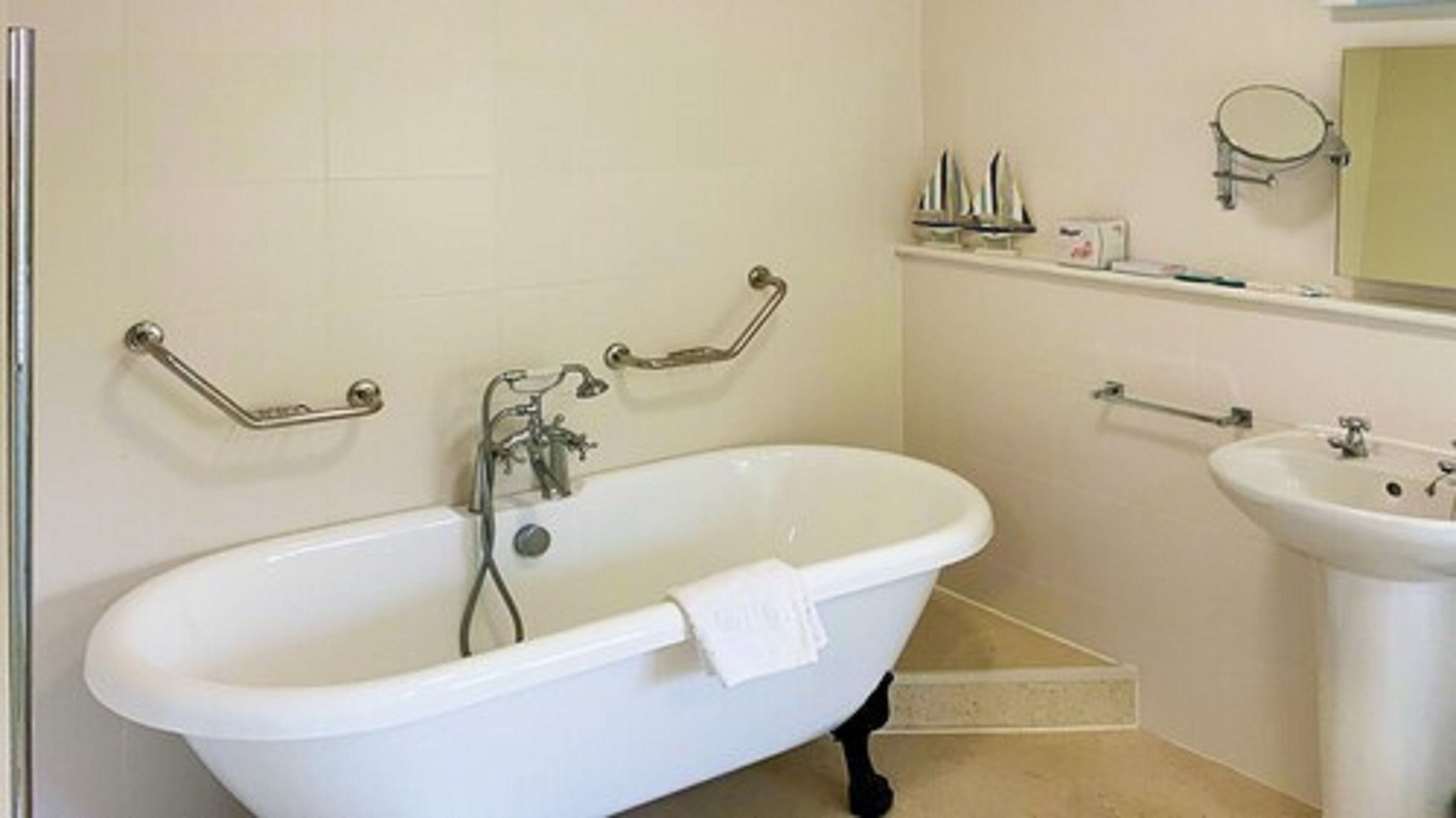 Een badkamer met een vrijstaand bad, een wastafel en een spiegel.