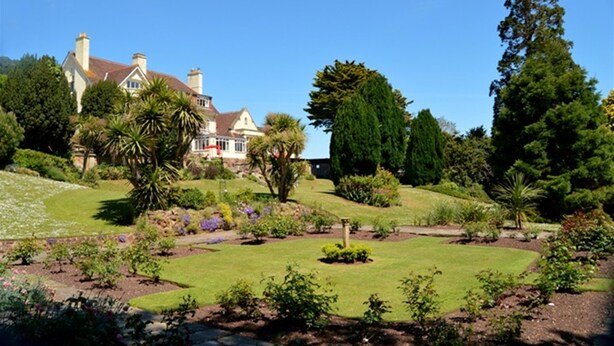 A large house with a well-maintained garden, including a lawn and various plants. - Northfield Hotel (Minehead)