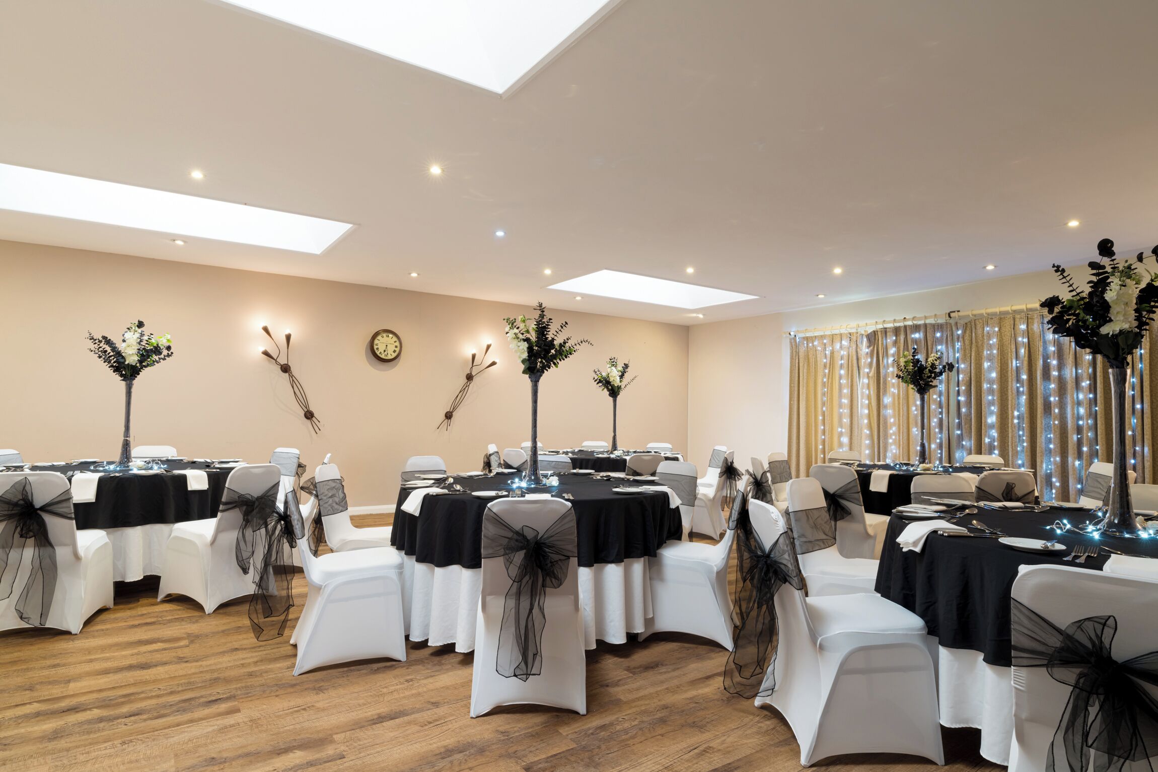 A conference room with tables set for a meeting, equipped with chairs, tables, and floral centerpieces.