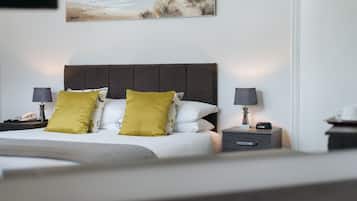 Una cama bien hecha con cabecera, dos mesitas de noche con lámparas y un cuadro sobre la cama.