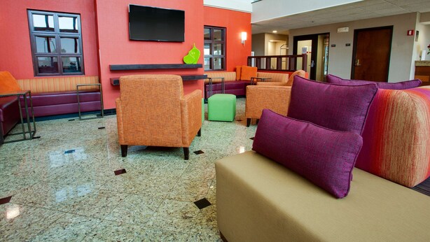 A lobby with seating areas, a flat-screen TV mounted on the wall, and a staircase leading to an upper level. - Drury Inn & Suites Terre Haute (Terre Haute)