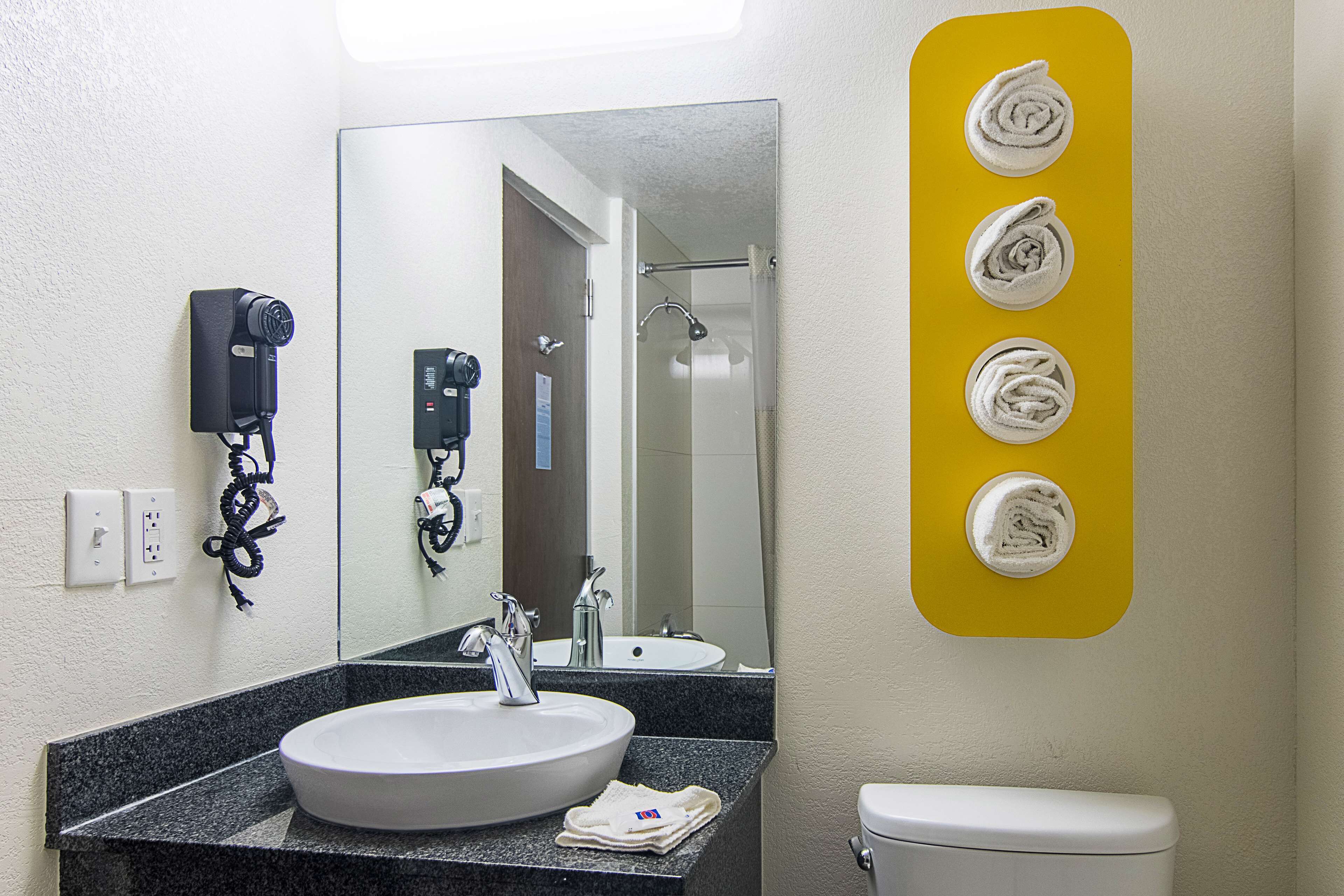 Een badkamer met wastafel, spiegel, zeepdispenser en toilet.