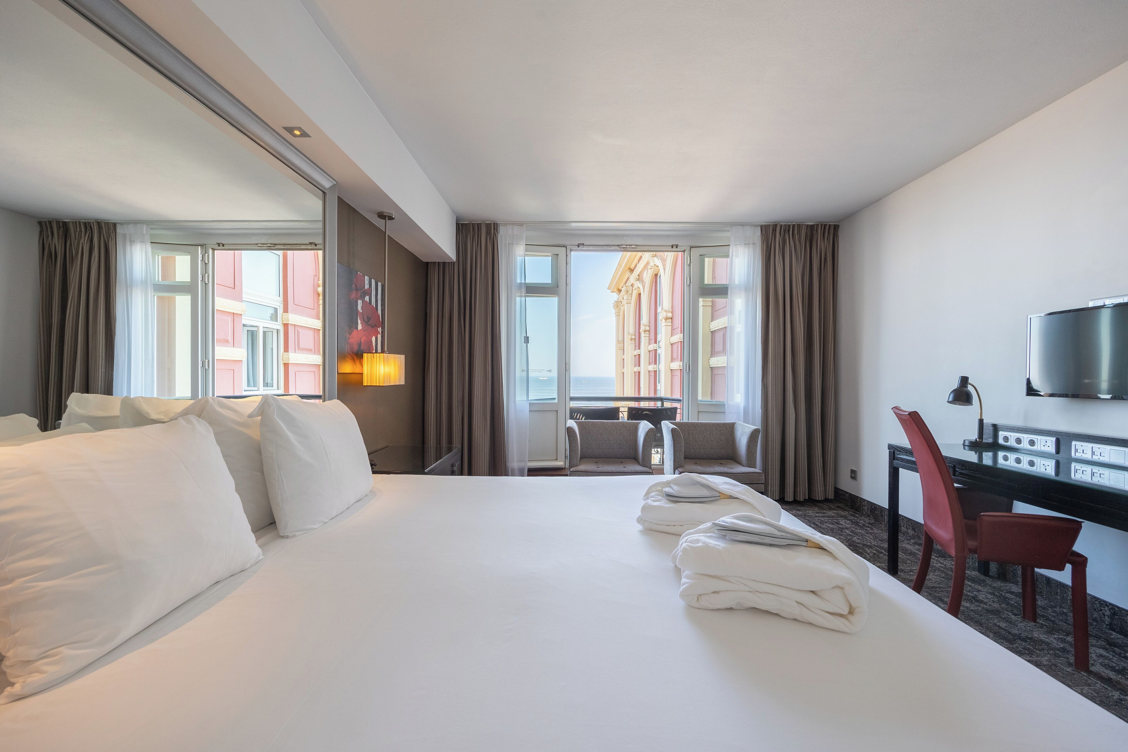 Een hotelkamer met een groot bed, een bureau, een stoel en een televisie.