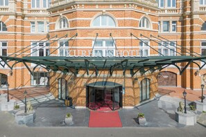 Classic hotel entrance with a red carpet leading to the glass door.
