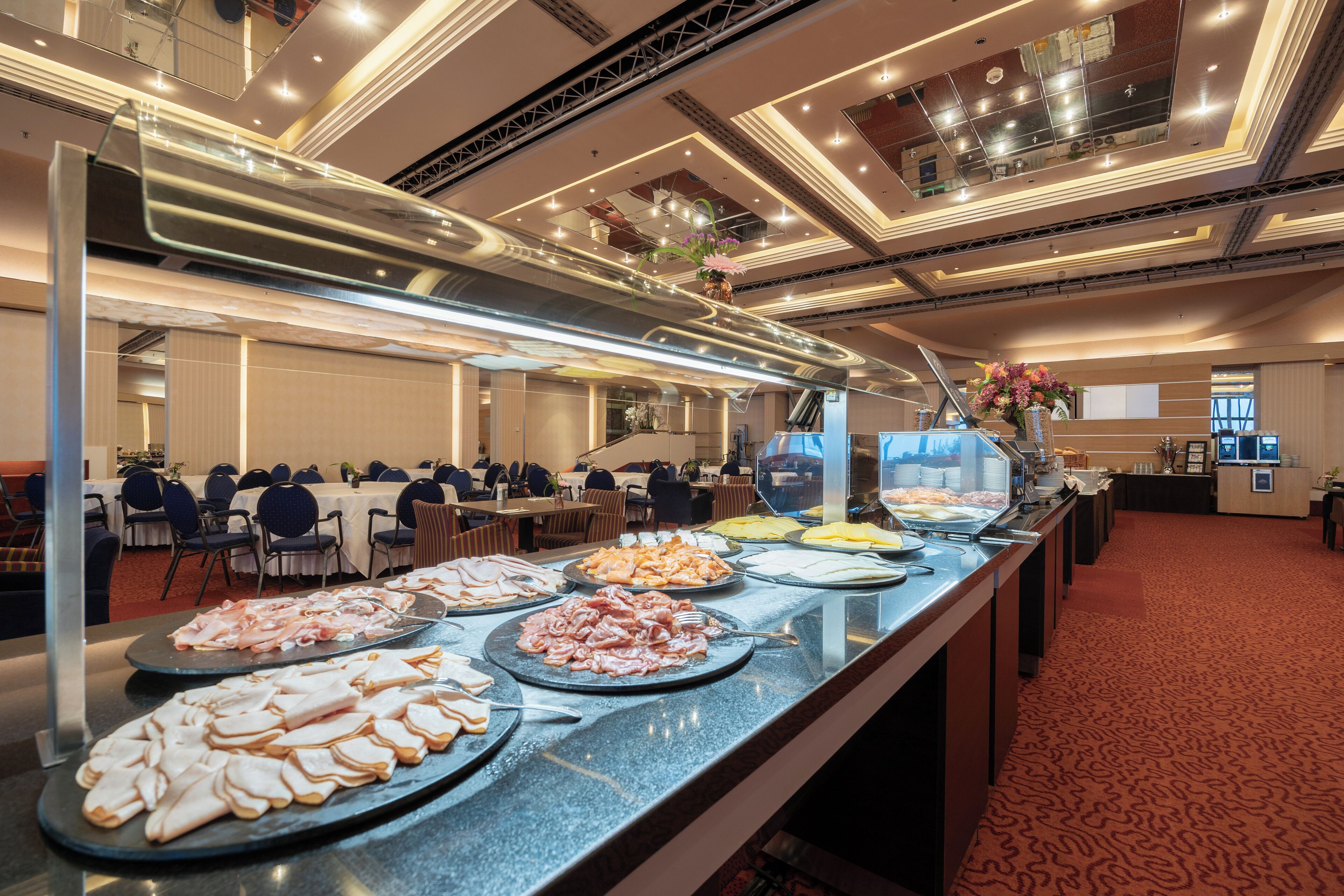 A buffet with various food items, a seating area with tables and chairs, and a modern interior design.