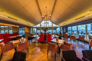 Enjoy meals in this well-lit dining area with a high ceiling and large windows offering views of the surrounding area.