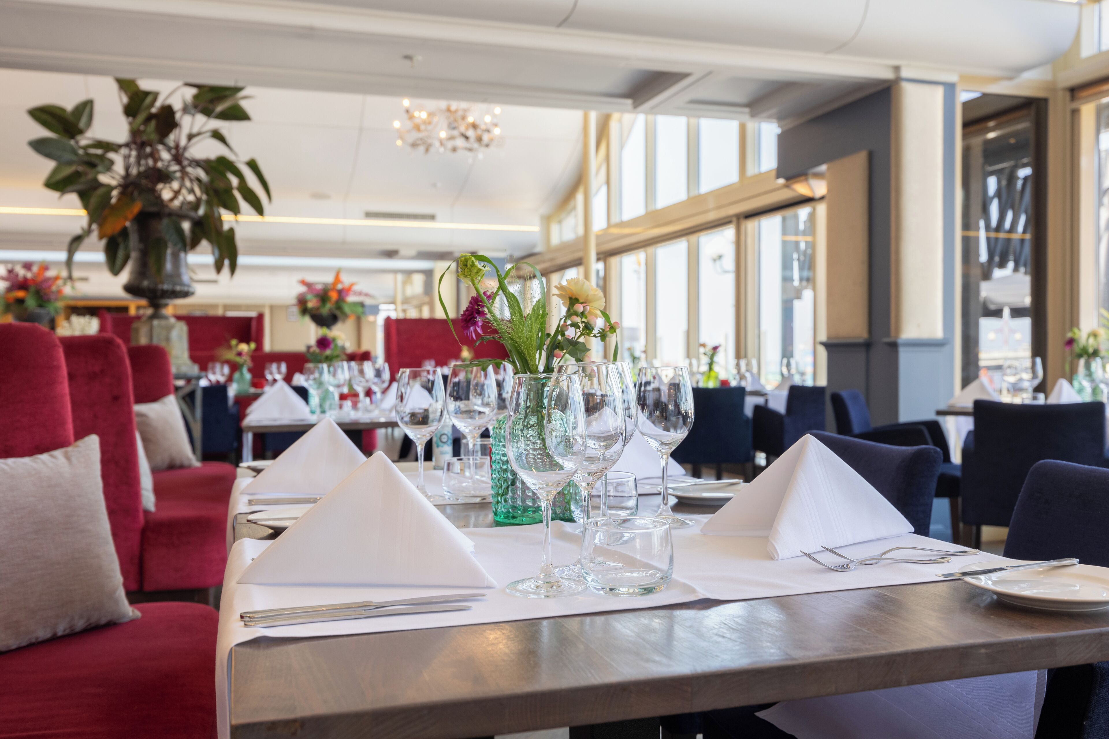 A restaurant setting with tables set for dining, featuring clear glassware and napkins.