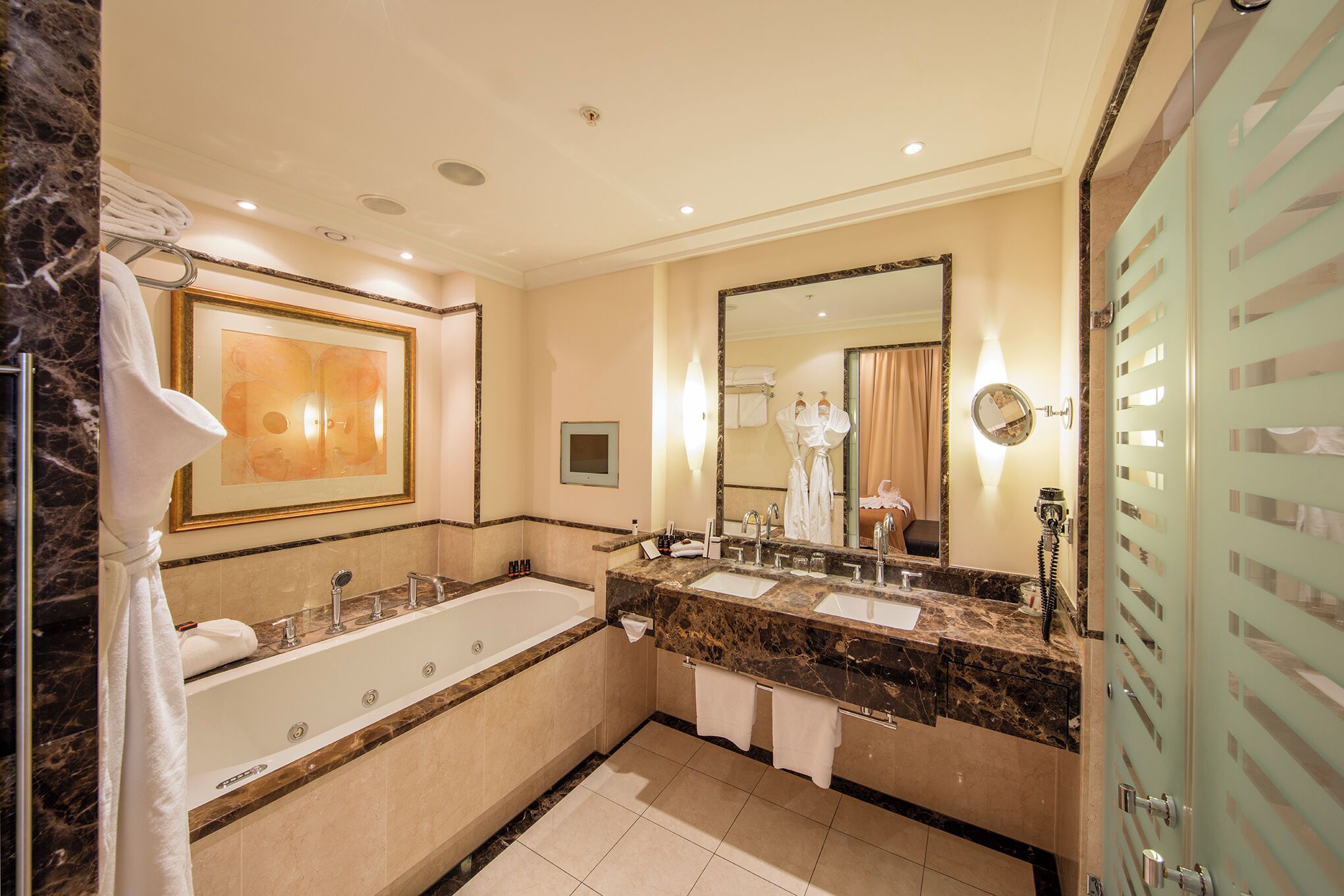 A spacious bathroom with a large bathtub, two sinks, and a large mirror.