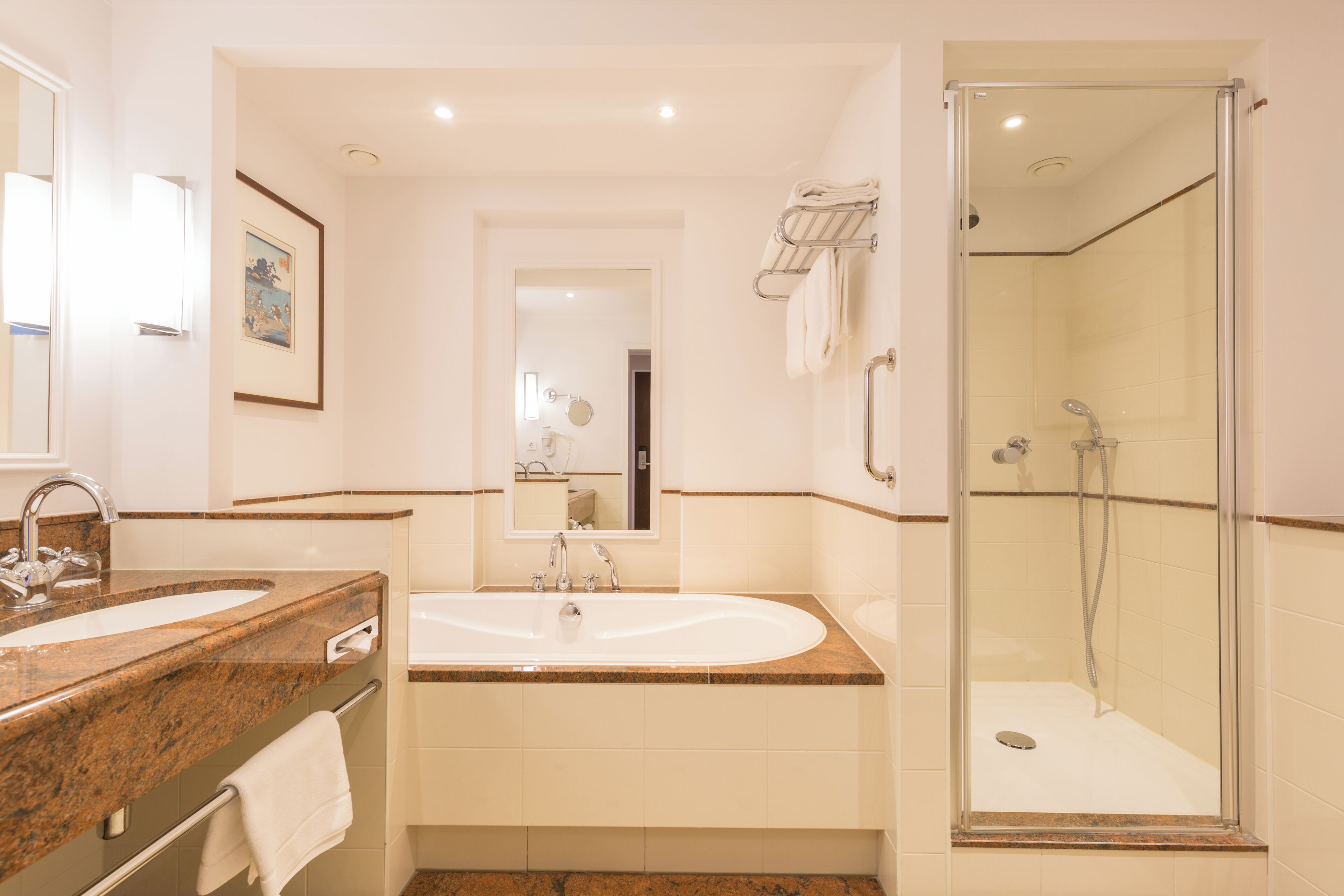 A modern bathroom with a granite countertop sink, a freestanding bathtub, and a glass-enclosed shower.