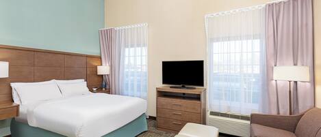 Ein Hotelzimmer mit Bett, Fernseher, Schreibtisch und Stuhl.