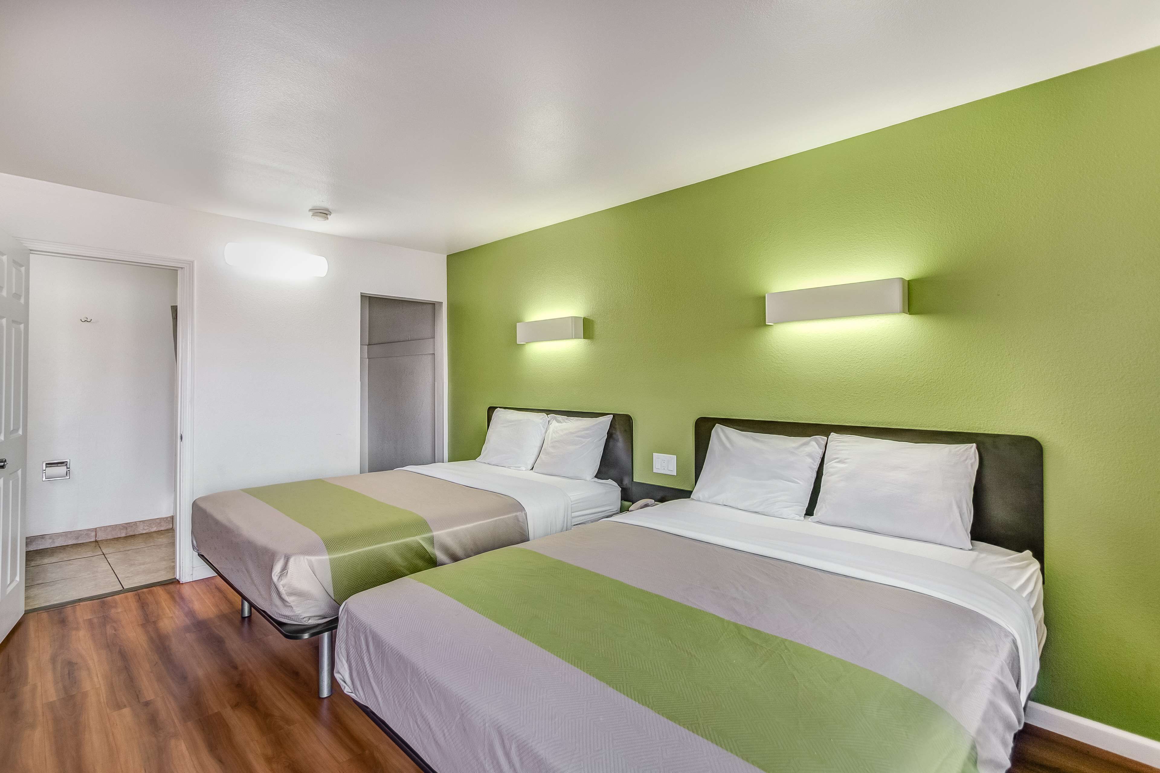 A hotel room with two beds, green walls, and a wooden floor.