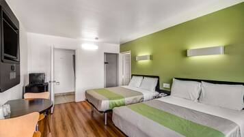 Habitación de hotel con dos camas, una mesita y sillas.