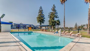 A swimming pool with lounge chairs and a building in the background.
